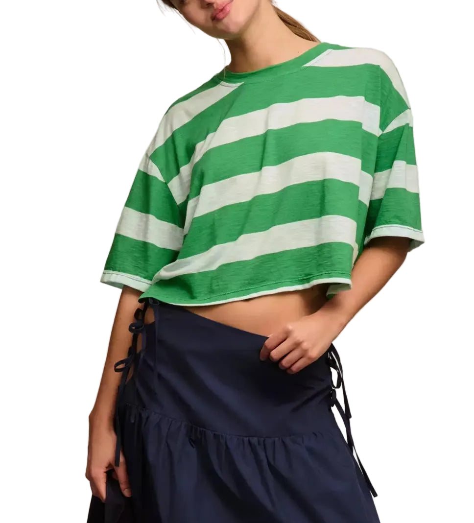 Woman wearing a green and white striped shirt with a navy skirt, holding a colorful bag.