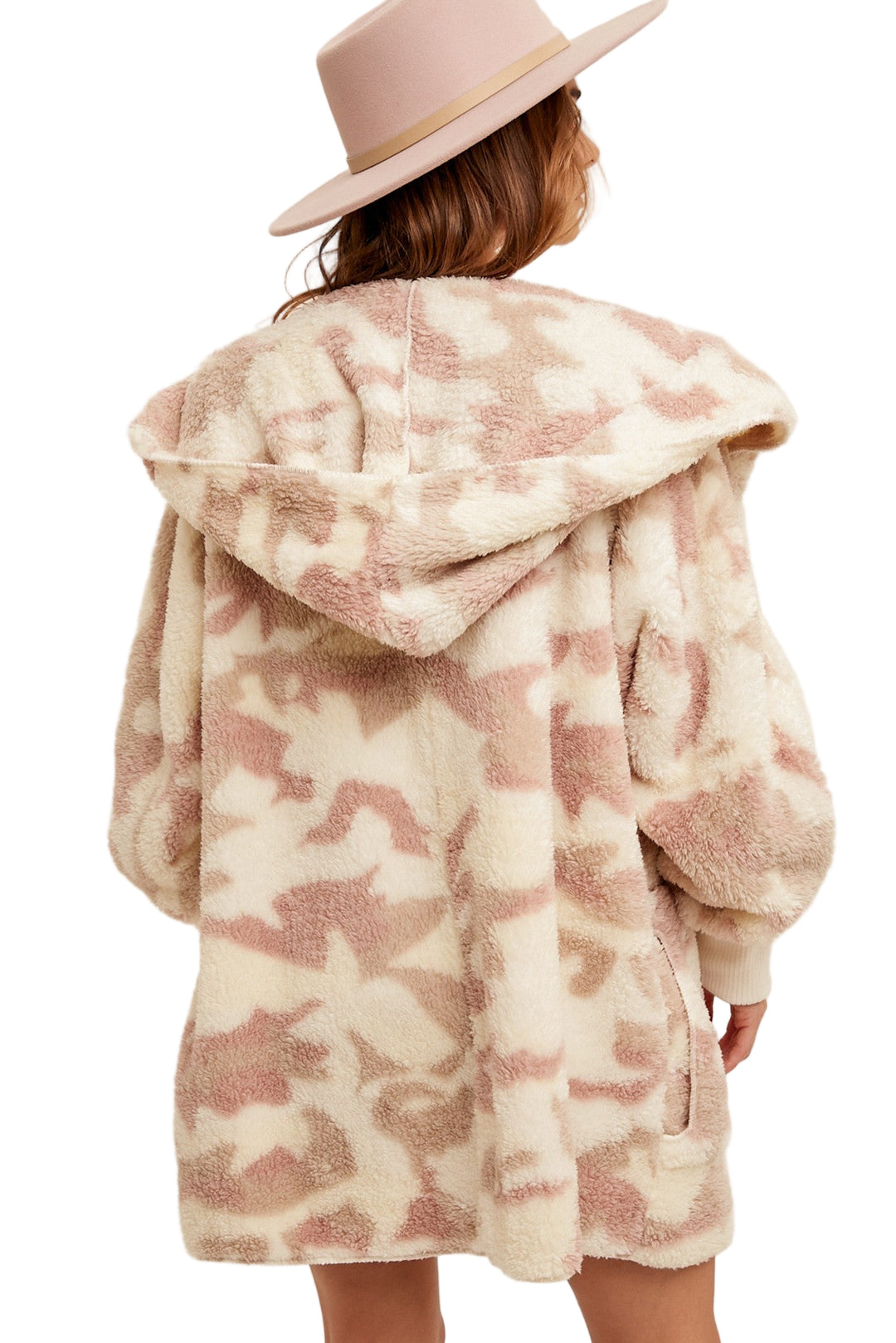 Person wearing a patterned coat and pink hat on a beige background