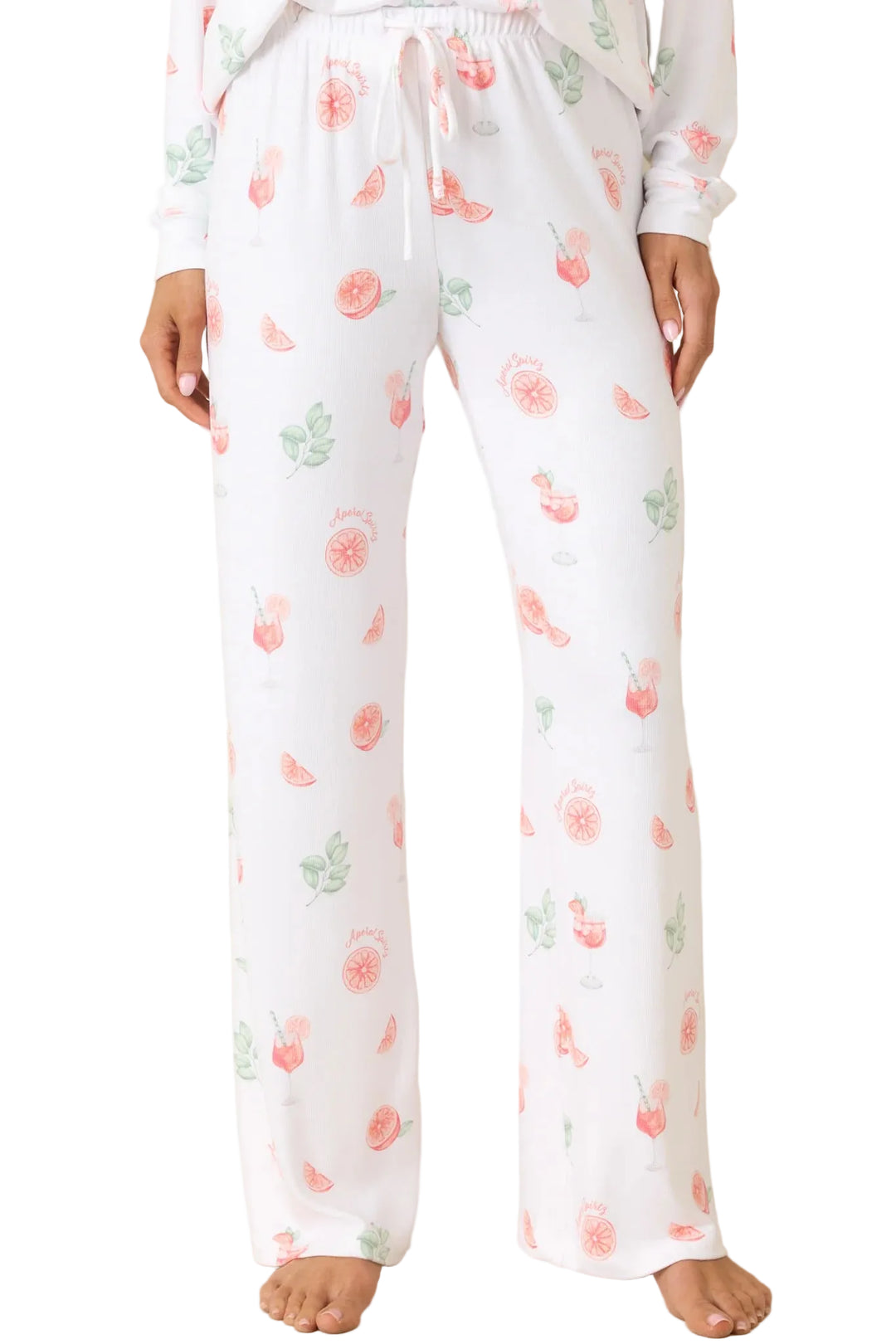 White pajama pants with a pink and green cherry print, featuring an elastic waistband with a white drawstring, shown on a model against a beige background.
