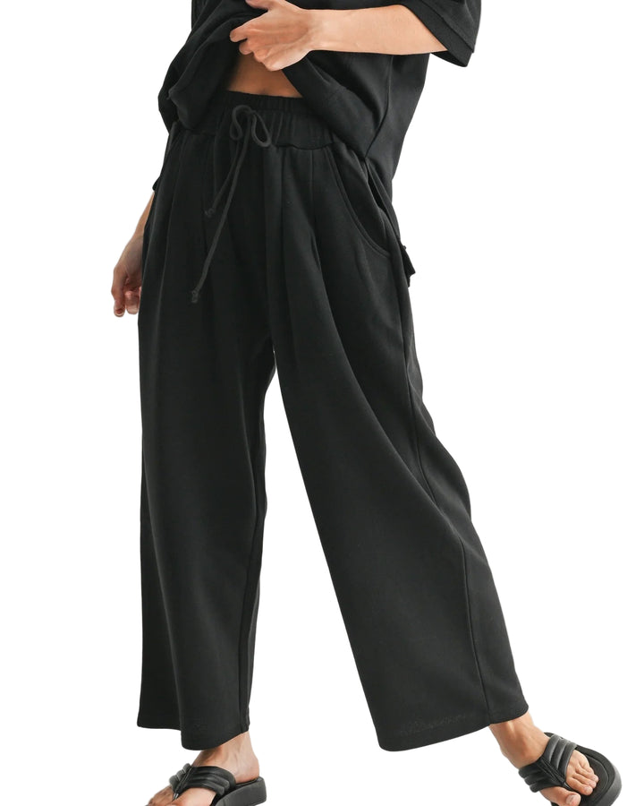 Person wearing black wide-leg pants on a plain background