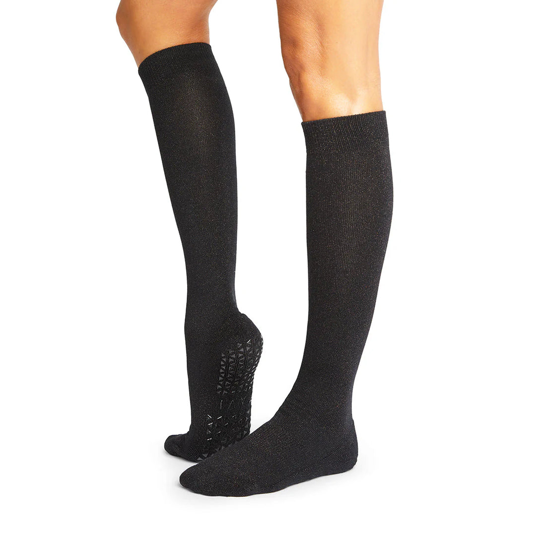 Black knee-high socks with textured sole on a white background