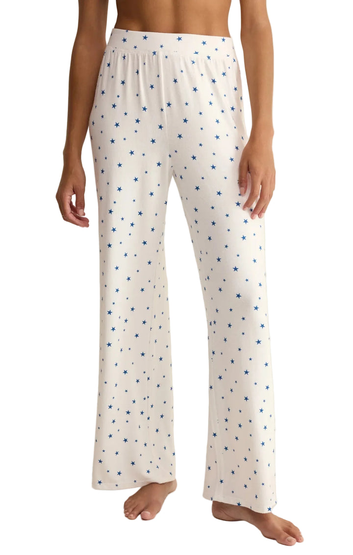 White pajama pants with blue star pattern worn by a person on a white background