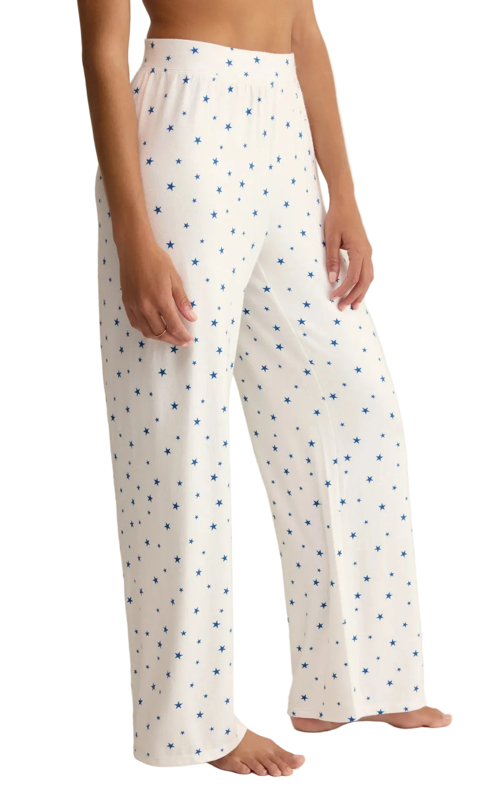 White pajama pants with blue stars worn by a person on a plain background