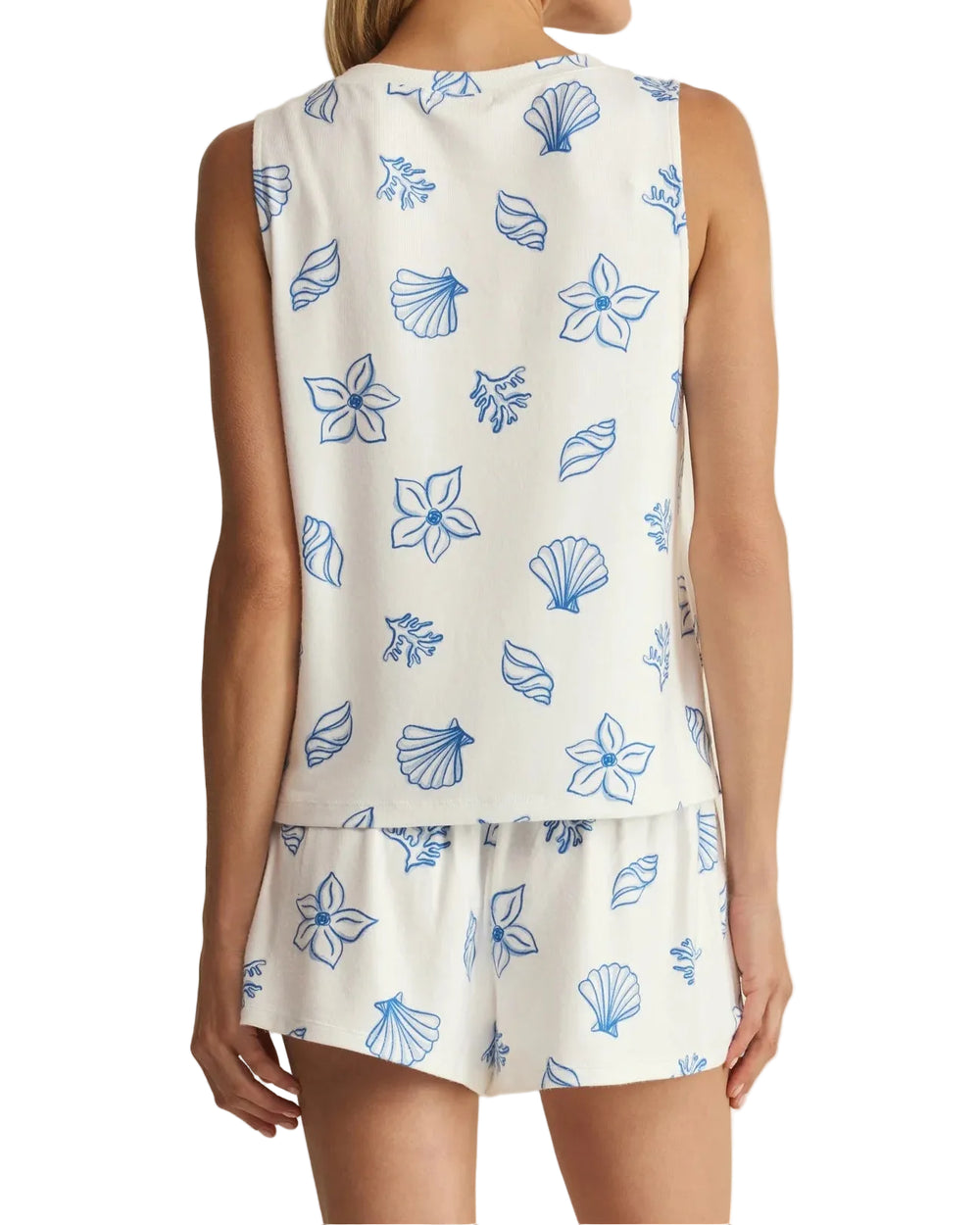 Woman wearing a sleeveless top and shorts with blue floral patterns on a beige background