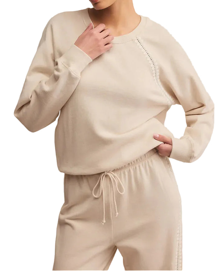 Woman wearing a beige sweater and pants set on a plain background