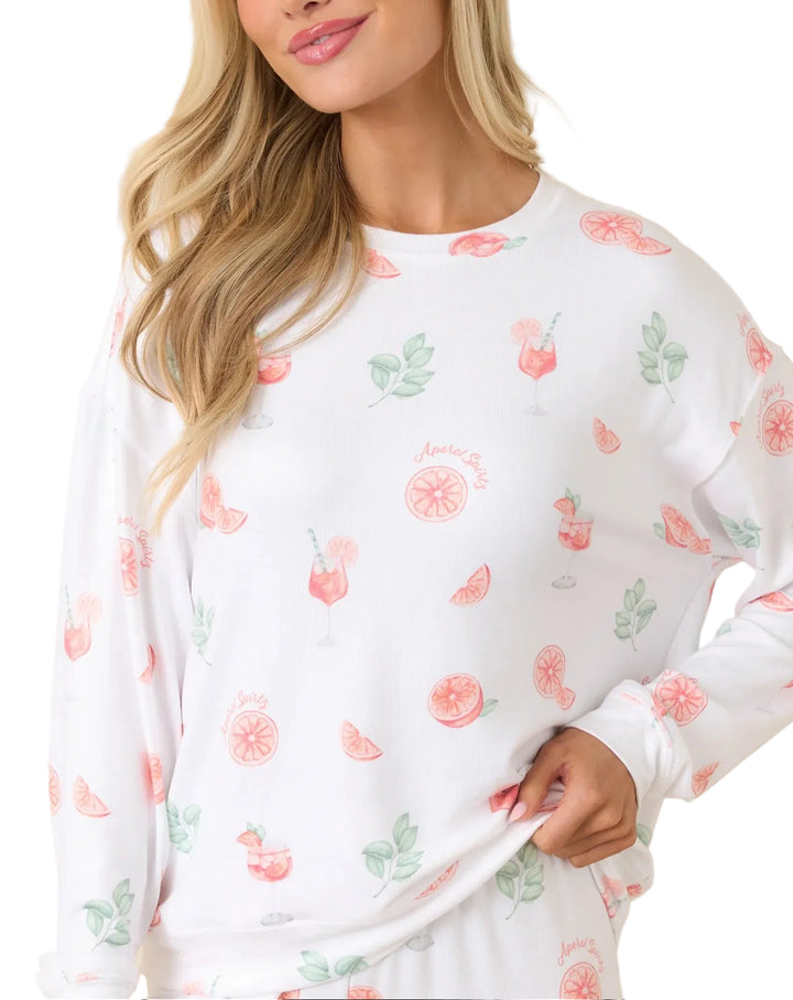 Woman wearing a white long-sleeve top with floral pattern against a beige background
