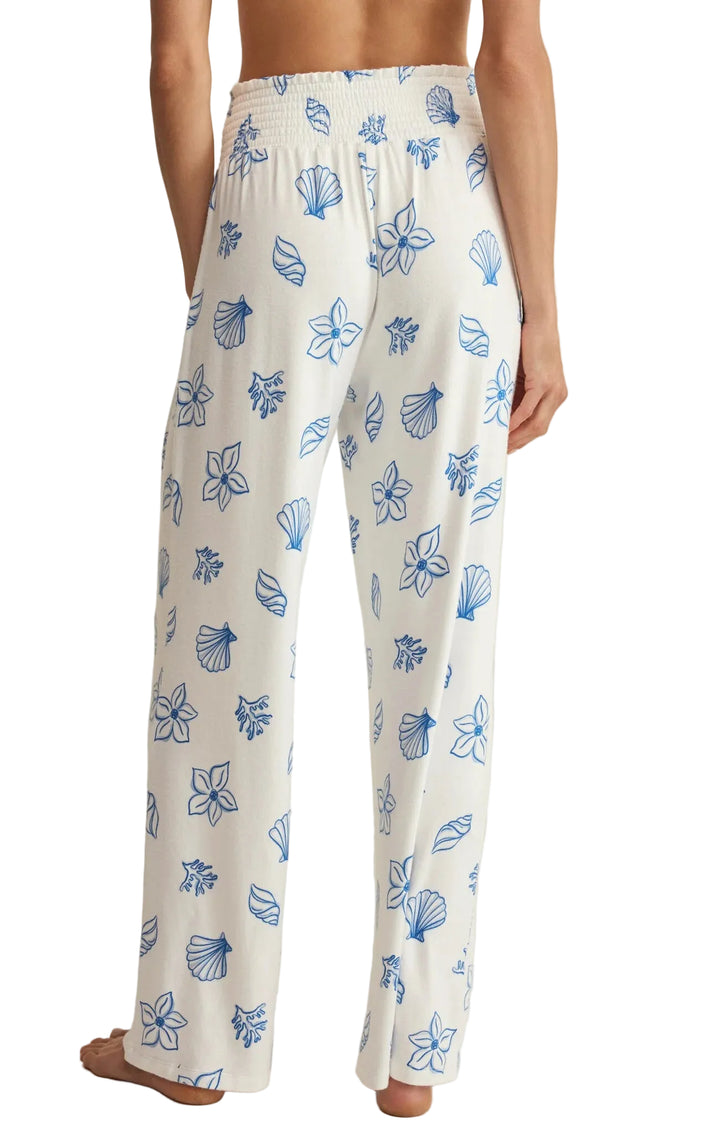 White pajama pants with blue floral pattern worn by a person on a neutral background